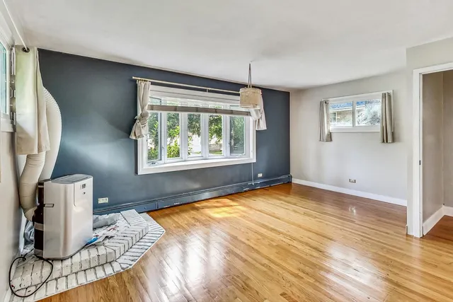 a view of an empty room with window and wooden floor