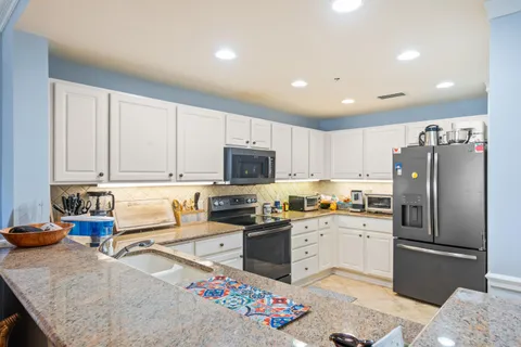 a kitchen with granite countertop a sink a counter top space appliances and cabinets