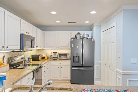 a kitchen with stainless steel appliances granite countertop a refrigerator stove microwave and sink
