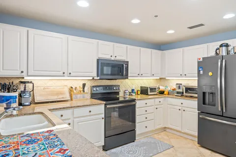 a kitchen with white cabinets and appliances