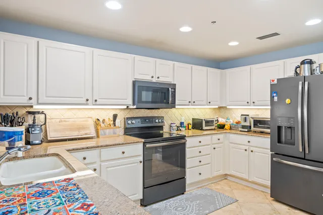 a kitchen with white cabinets and appliances