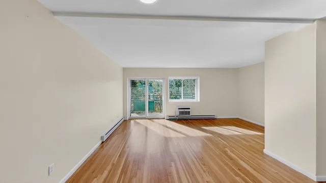 a view of an empty room with a window and wooden floor