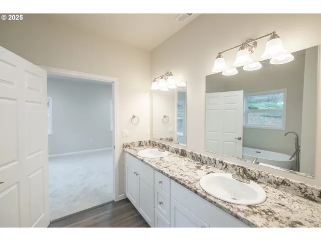 a bathroom with a granite countertop double vanity sink mirror and shower