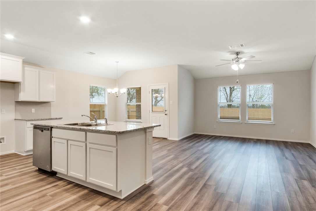 a kitchen with stainless steel appliances granite countertop a stove a sink dishwasher and a refrigerator with wooden floors
