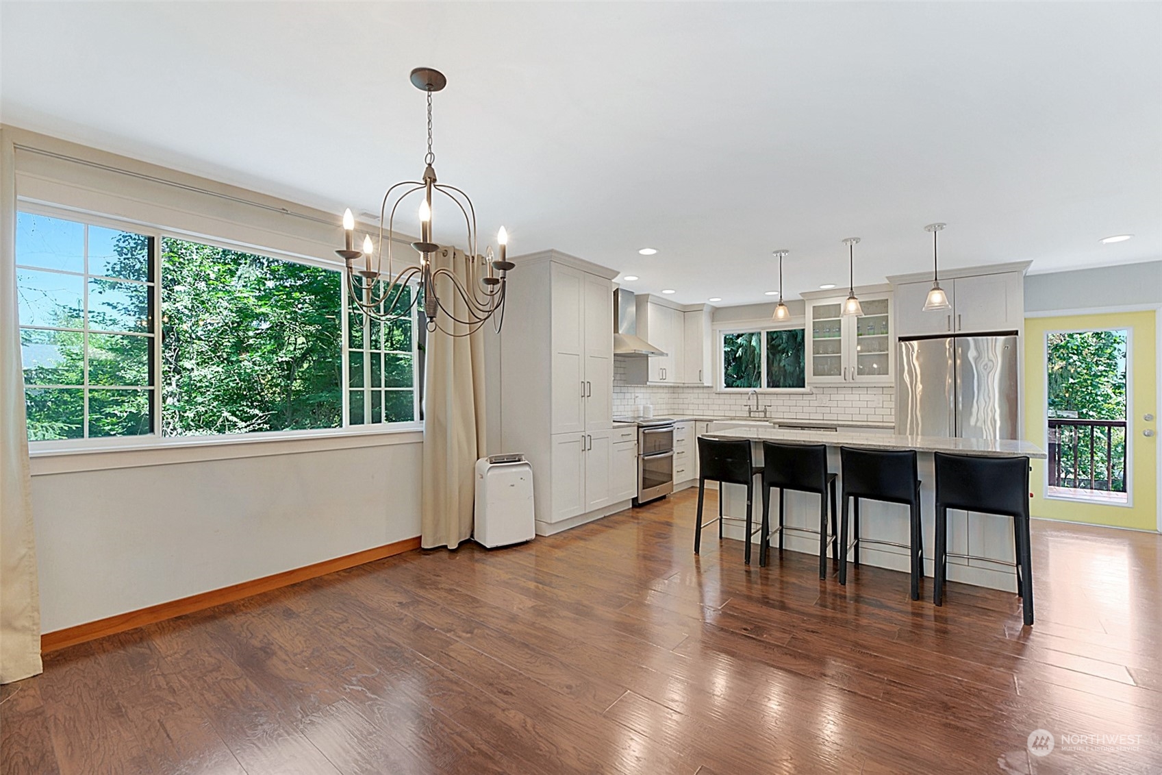907 Harvest Road Bothell, WA 98012 - Photo 8 of 28 a kitchen with stainless steel appliances kitchen island granite countertop a stove top oven a dining table and chairs with wooden floor