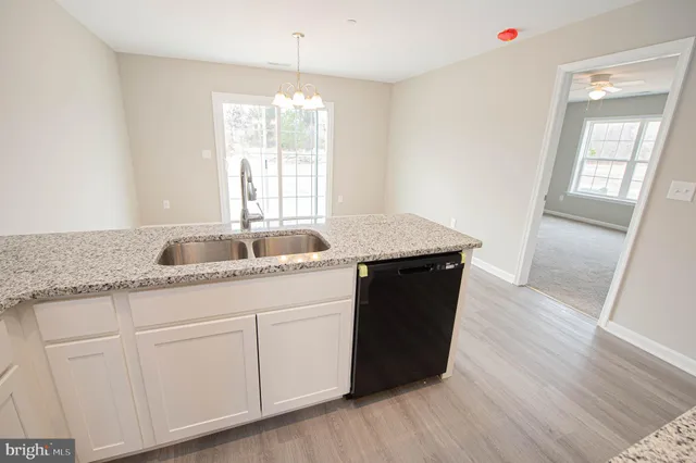 a living room with stainless steel appliances granite countertop furniture wooden floor and a view of kitchen