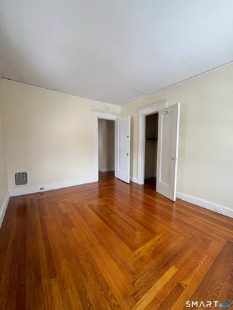 a view of an empty room with wooden floor and closet
