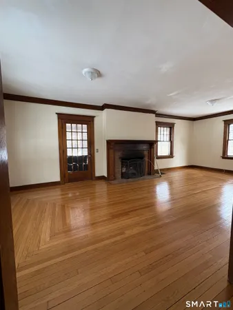 an empty room with wooden floor fireplace and windows