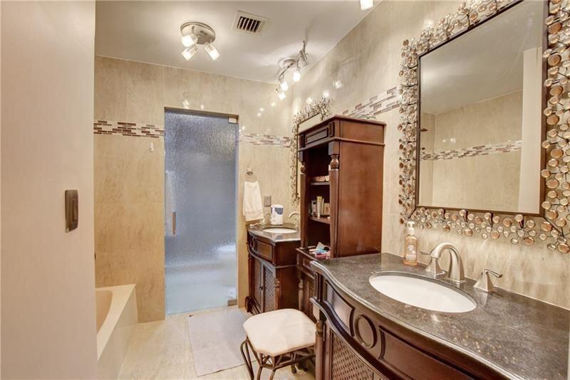 7448 La Paz Boulevard, Unit 104 Boca Raton, FL 33433 - Photo 13 of 16 a bathroom with a granite countertop sink a toilet a mirror and shower