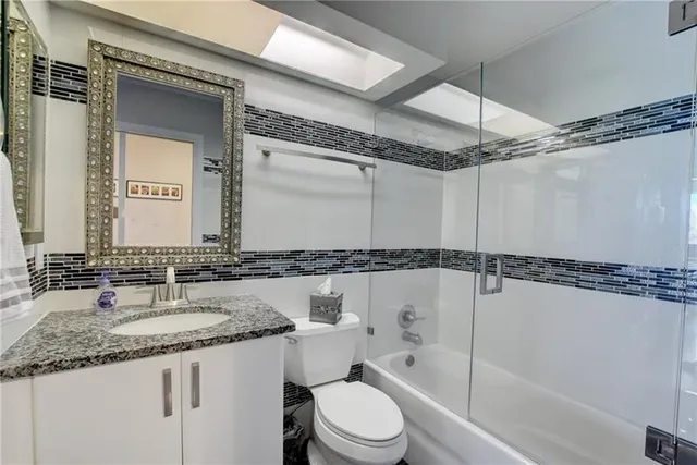 a bathroom with a granite countertop sink mirror vanity and toilet
