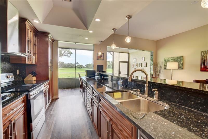 7448 La Paz Boulevard, Unit 104 Boca Raton, FL 33433 - Photo 3 of 16 a kitchen with granite countertop a sink a counter top space cabinets and stainless steel appliances