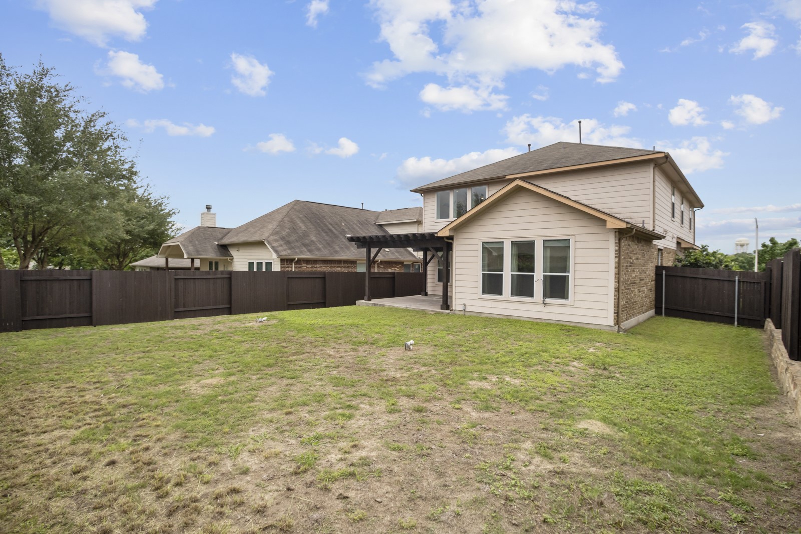 245 Razzmatazz Trail Buda, TX 78610 - Photo 35 of 37 Expansive backyard featuring a privacy fence, concrete patio, and pergola structure