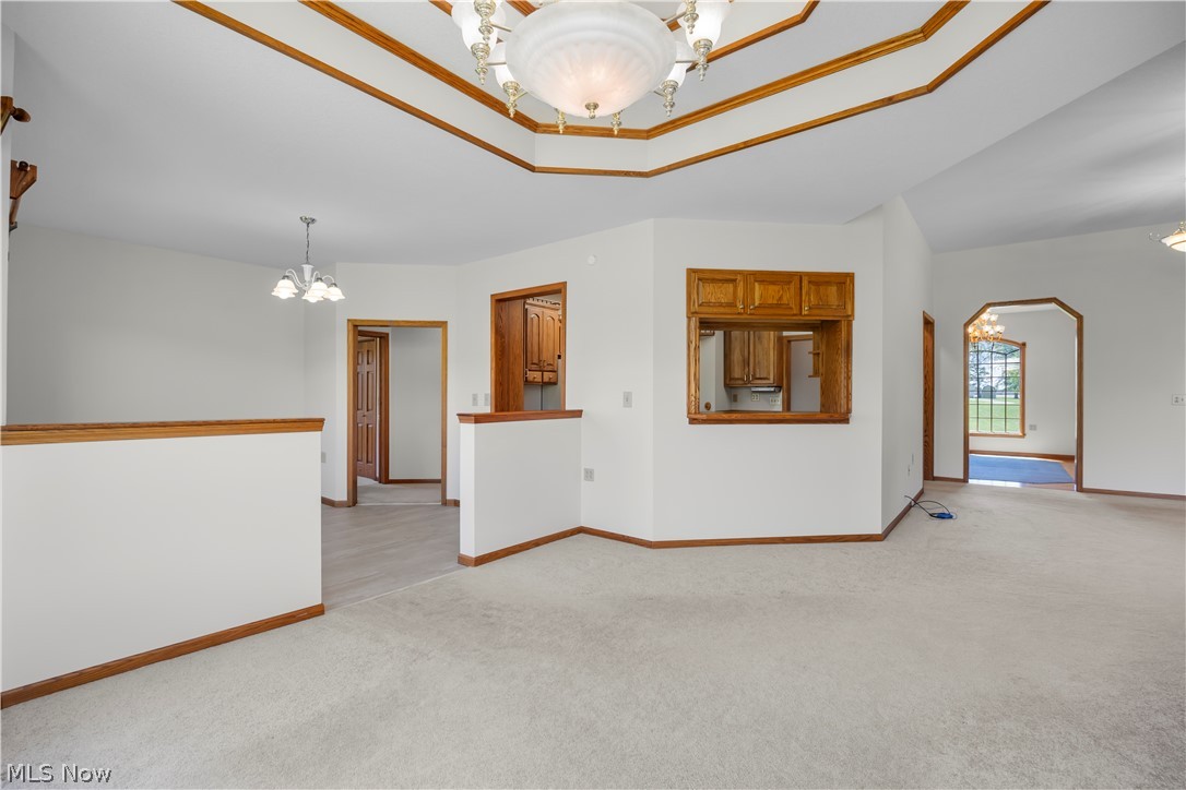 51488 Peck Wadsworth Road Wellington, OH 44090 - Photo 25 of 50 Tray ceiling with wood-finish trim, a central chandelier, and recessed lighting