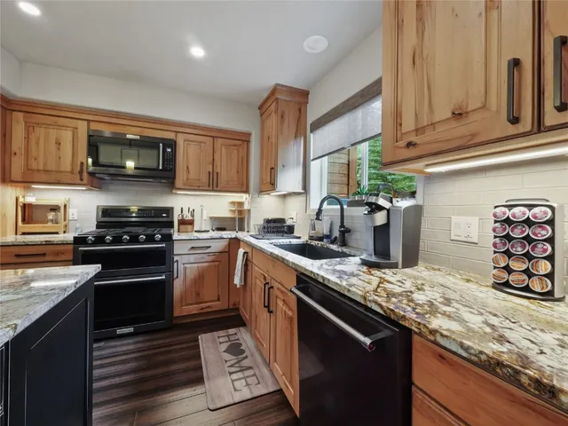a kitchen with stainless steel appliances granite countertop a stove a sink and a microwave