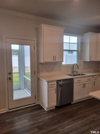 a kitchen with granite countertop wooden cabinets a sink and dishwasher a stove with wooden floor