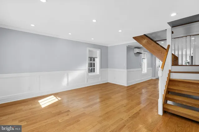 a view of an empty room with wooden floor and stairs
