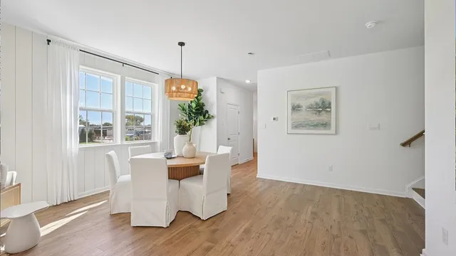 a kitchen with stainless steel appliances kitchen island granite countertop a stove top oven a sink a refrigerator with white cabinets and wooden floor