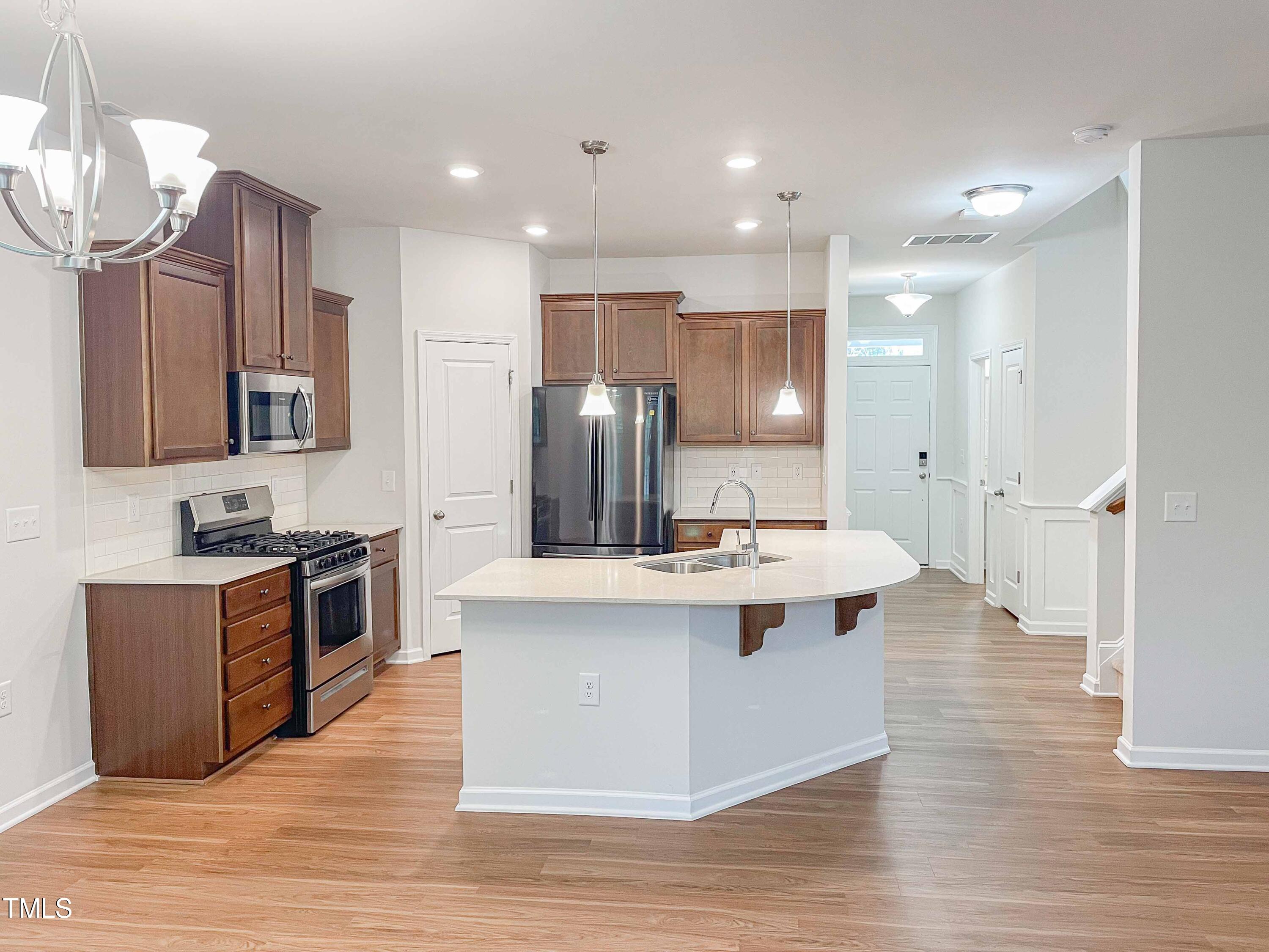 6027 Beale Loop Raleigh, NC 27616 - Photo 5 of 21 a large kitchen with stainless steel appliances a stove a sink dishwasher a refrigerator and a dining table with wooden floor