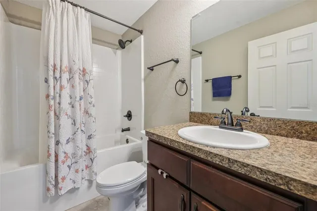a bathroom with a granite countertop sink toilet mirror and shower