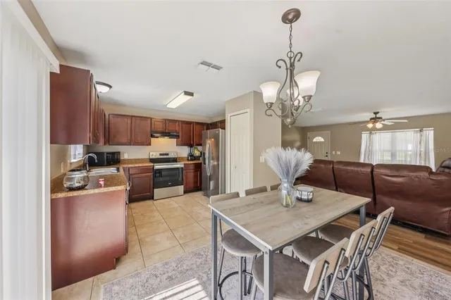 a kitchen with kitchen island a dining table chairs stainless steel appliances and cabinets