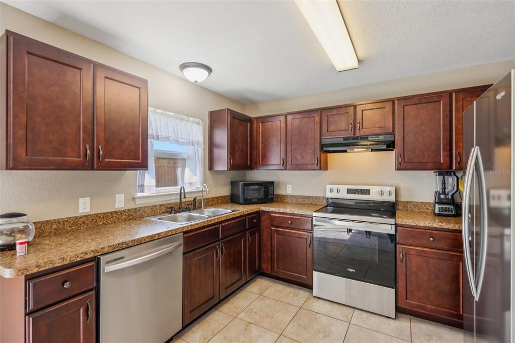 176 Juniper Loop Circle Ocala, FL 34480 - Photo 8 of 21 a kitchen with stainless steel appliances granite countertop wooden cabinets a sink and dishwasher a stove top oven with wooden floor