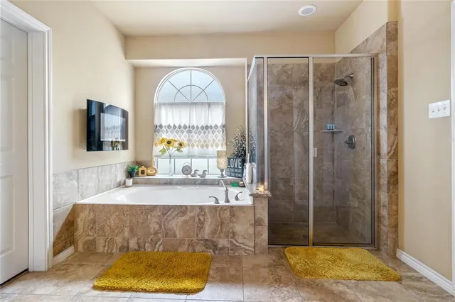 a bathroom with a tub a window and glass door shower