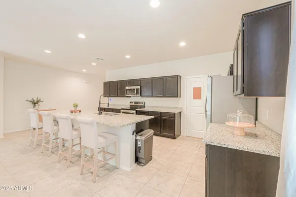 a kitchen with stainless steel appliances kitchen island granite countertop a sink refrigerator and cabinets