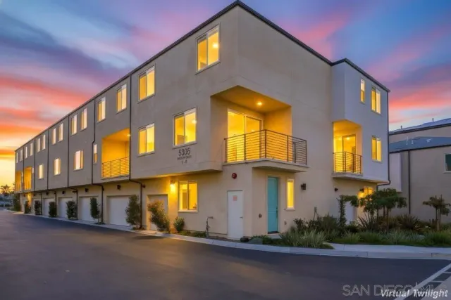 a front view of a multi story residential apartment building with garage and plants