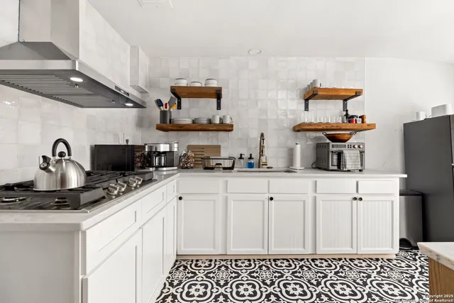 a kitchen with stainless steel appliances a sink a stove and white cabinets