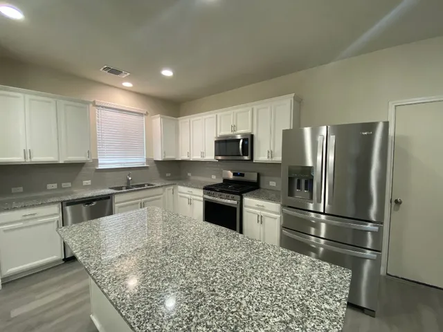 a kitchen with granite countertop a refrigerator and a sink