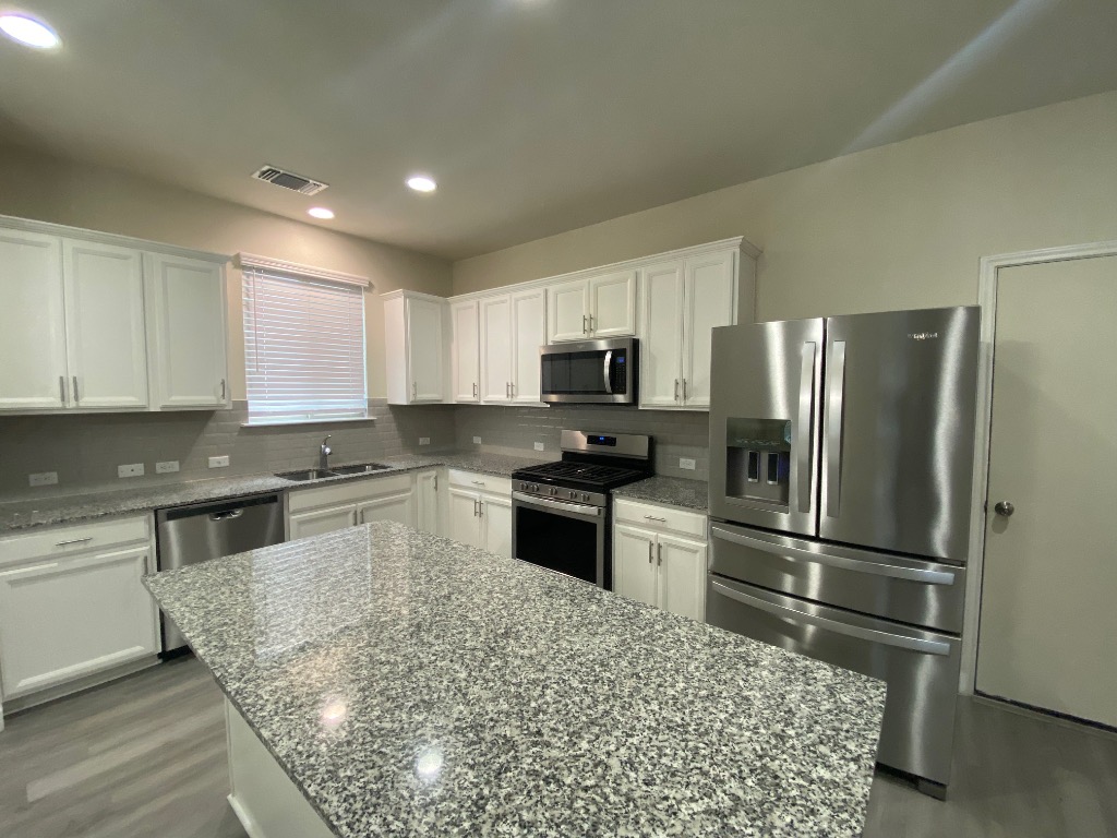 97 Quarryman Drive Hutto, TX 78634 - Photo 11 of 37 a kitchen with granite countertop a refrigerator and a sink