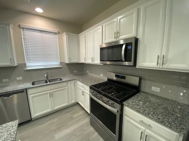 a kitchen with granite countertop a sink cabinets and stainless steel appliances