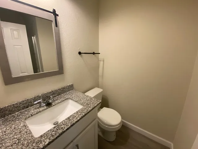 a bathroom with a granite countertop sink toilet and mirror