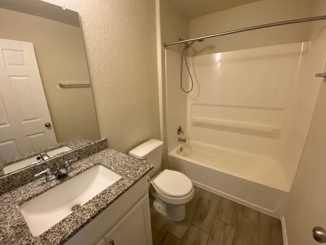 a bathroom with a granite countertop sink toilet and shower