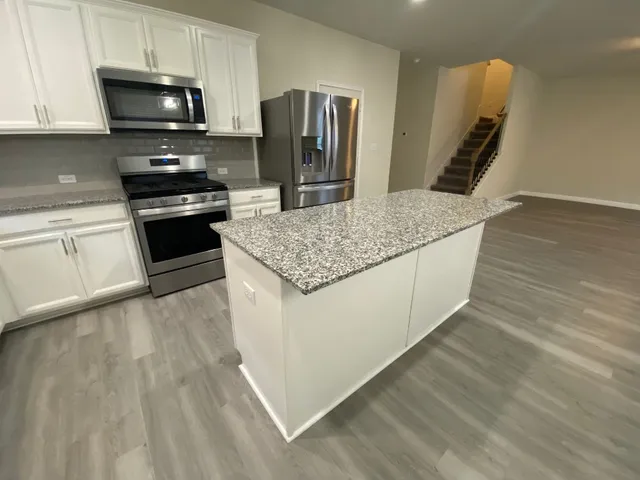 a kitchen with granite countertop a refrigerator stove and microwave