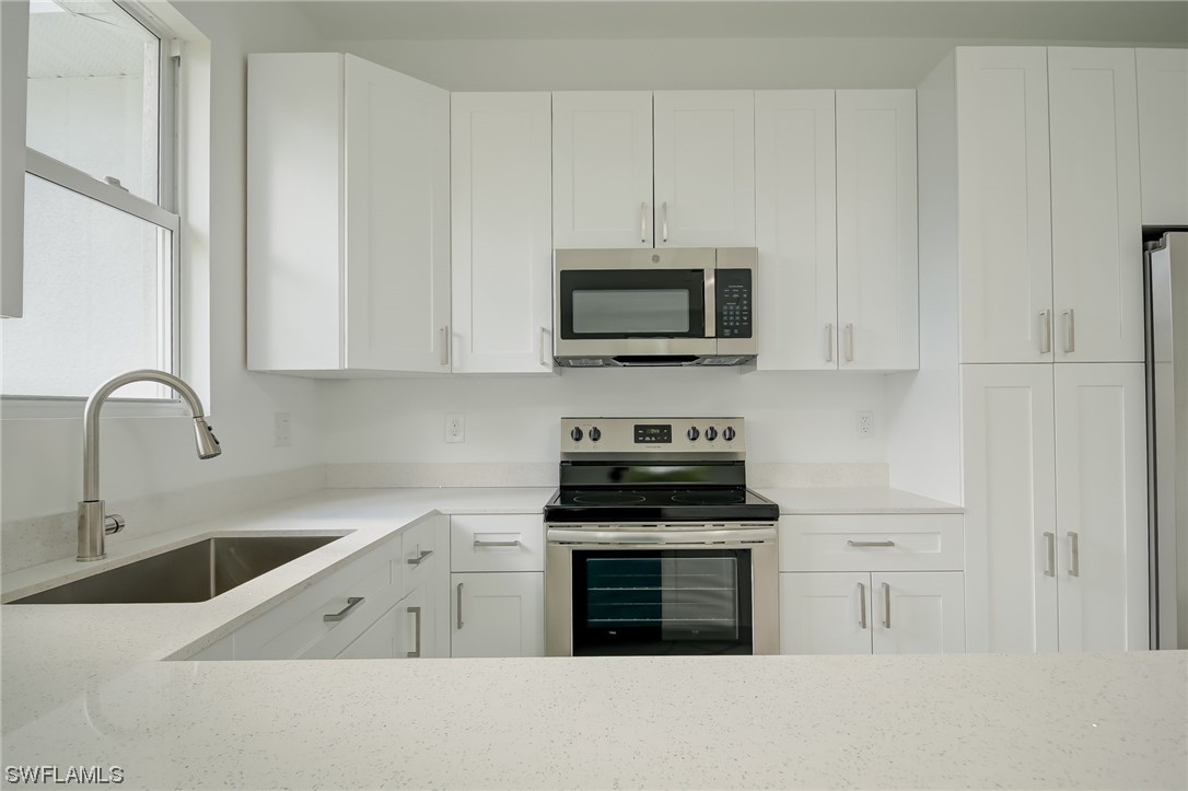 6017 Ruth Avenue North Lehigh Acres, FL 33971 - Photo 4 of 25 a kitchen with stainless steel appliances granite countertop a stove a sink and a microwave