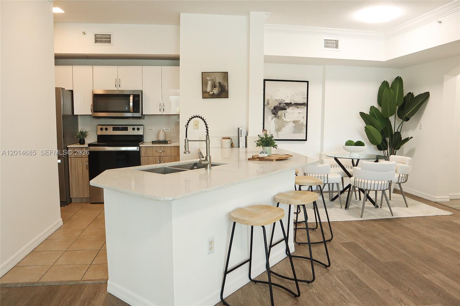 9172 Collins Avenue, Unit 212 Surfside, FL 33154 - Photo 7 of 23 a kitchen with stainless steel appliances a kitchen island a stove a table and chairs with wooden floor