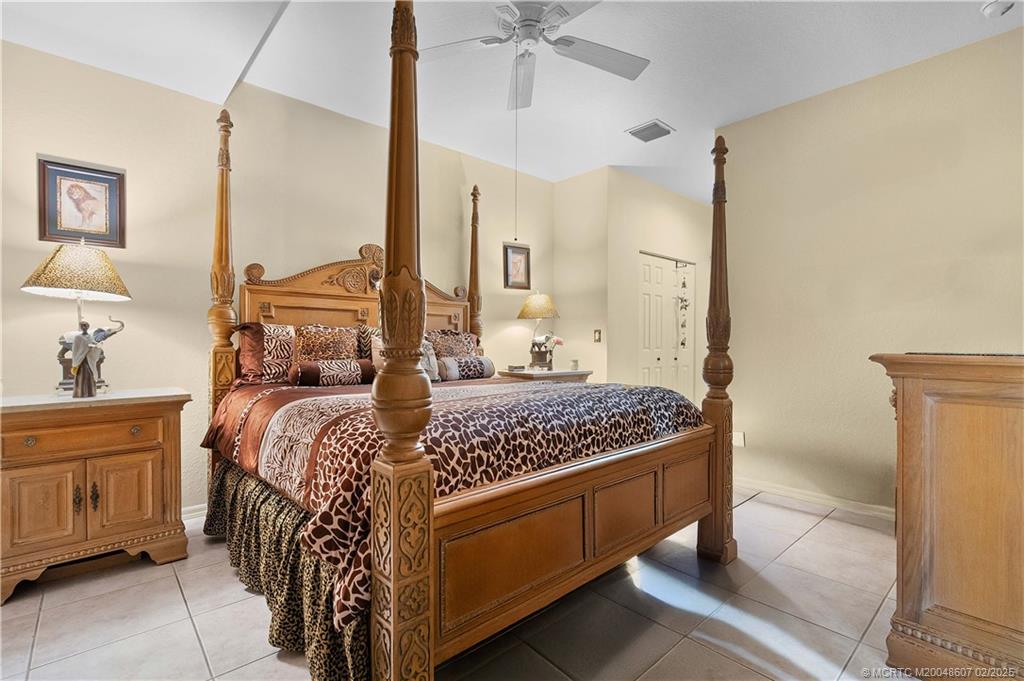 1580 Southeast Sheffield Terrace, Unit 101 Stuart, FL 34994 - Photo 16 of 39 a bedroom with a bed and a chandelier