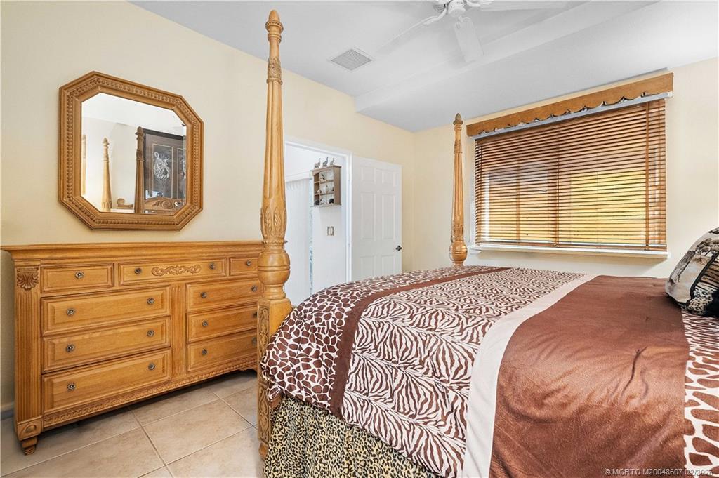 1580 Southeast Sheffield Terrace, Unit 101 Stuart, FL 34994 - Photo 17 of 39 a bedroom with a bed and a mirror on the dresser