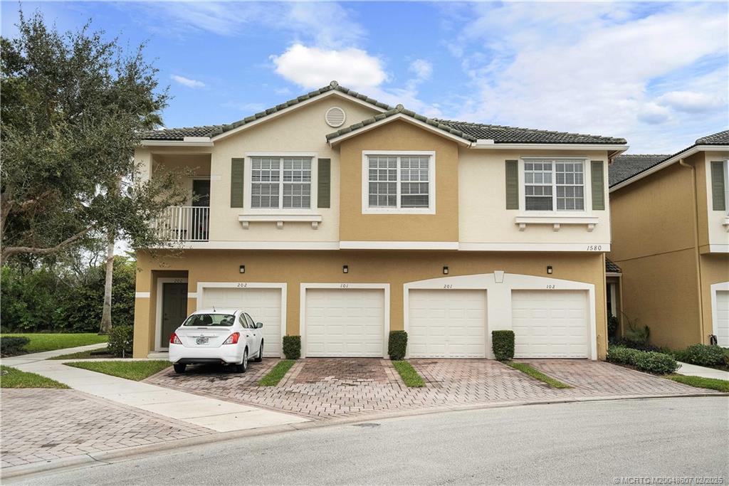 1580 Southeast Sheffield Terrace, Unit 101 Stuart, FL 34994 - Photo 3 of 39 a front view of a house with a yard and garage