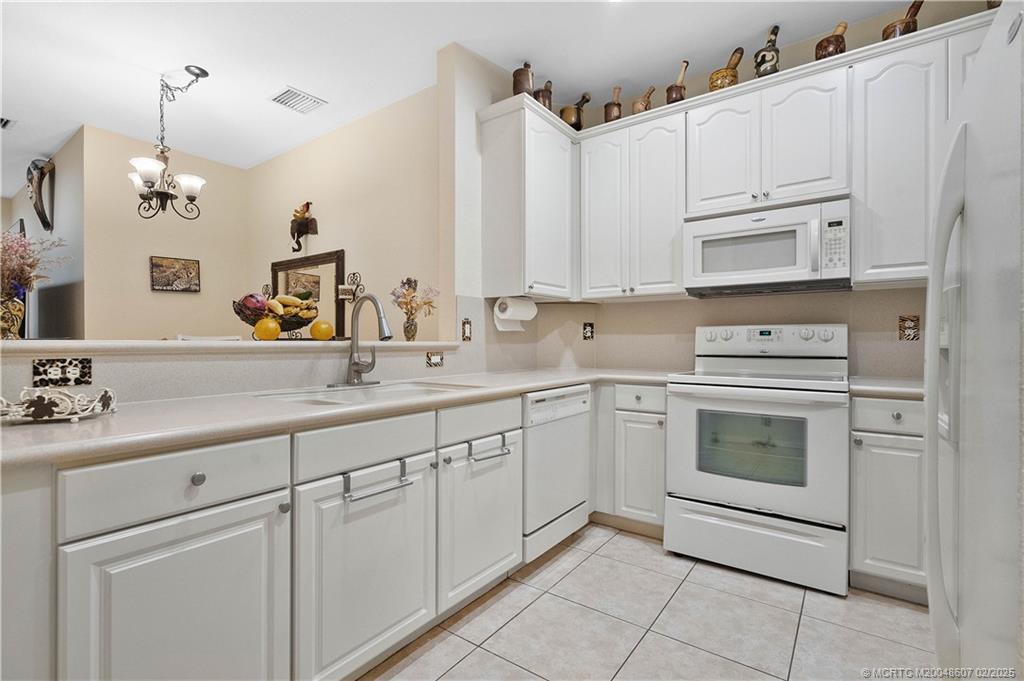 1580 Southeast Sheffield Terrace, Unit 101 Stuart, FL 34994 - Photo 6 of 39 a kitchen with white cabinets and white appliances