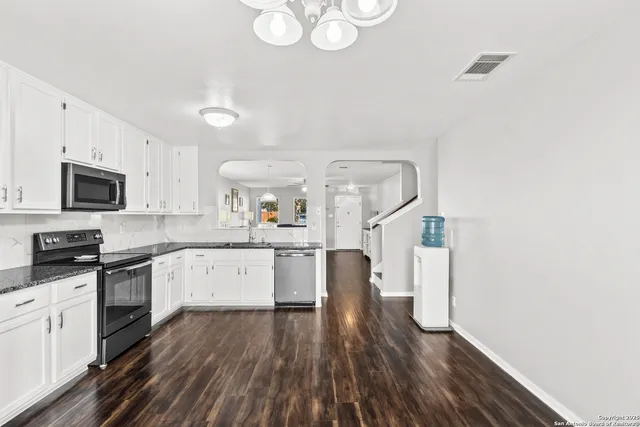 a kitchen with granite countertop a stove top oven a sink dishwasher and a microwave with wooden floor