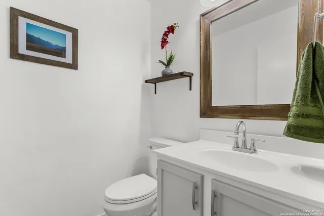 a bathroom with a granite countertop toilet sink and mirror