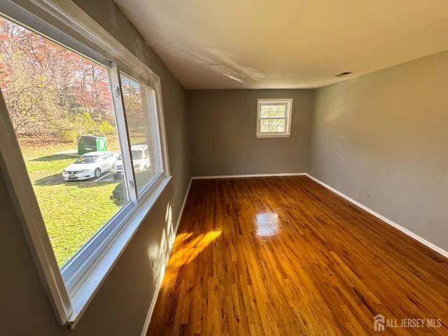 a view of an empty room with a window and wooden floor