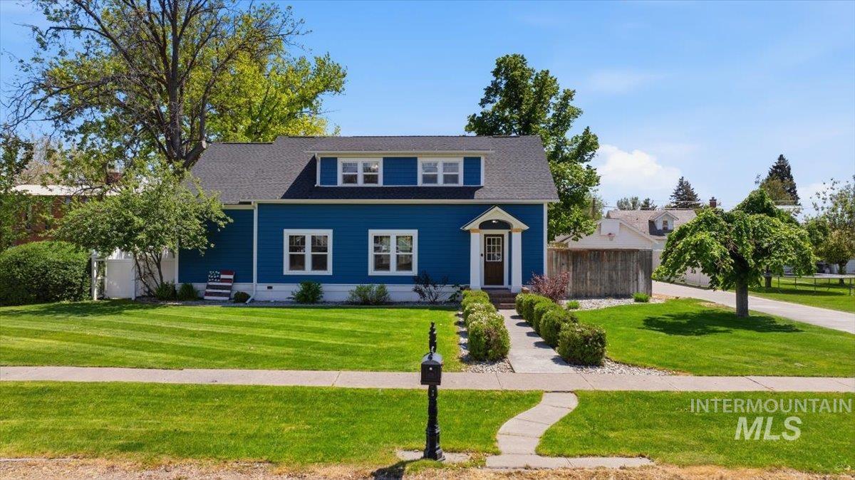 Dormer-style residence featuring blue siding, white window trim, and a dark shingle roof
