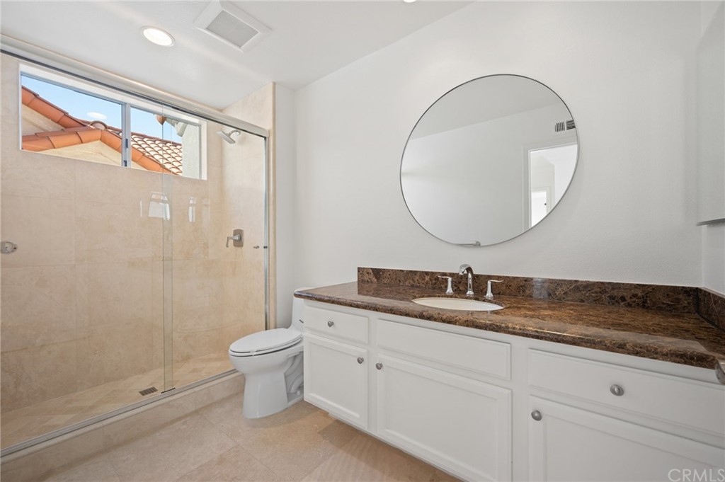 17 St John Dana Point, CA 92629 - Photo 22 of 28 a bathroom with a granite countertop toilet a sink and a mirror