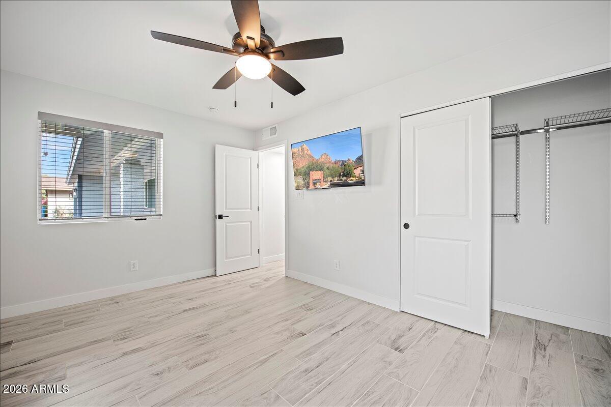 11615 North 30th Street Phoenix, AZ 85028 - Photo 23 of 37 an empty room with wooden floor ceiling fan and windows