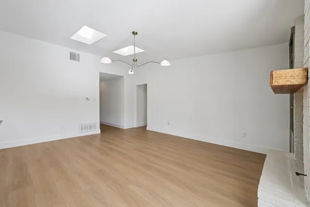 an empty room with wooden floor and ceiling fan