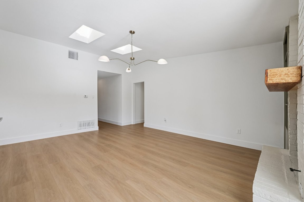 10424 Quail Ridge Drive Austin, TX 78758 - Photo 10 of 37 Spare room with a skylight and light wood-style floors