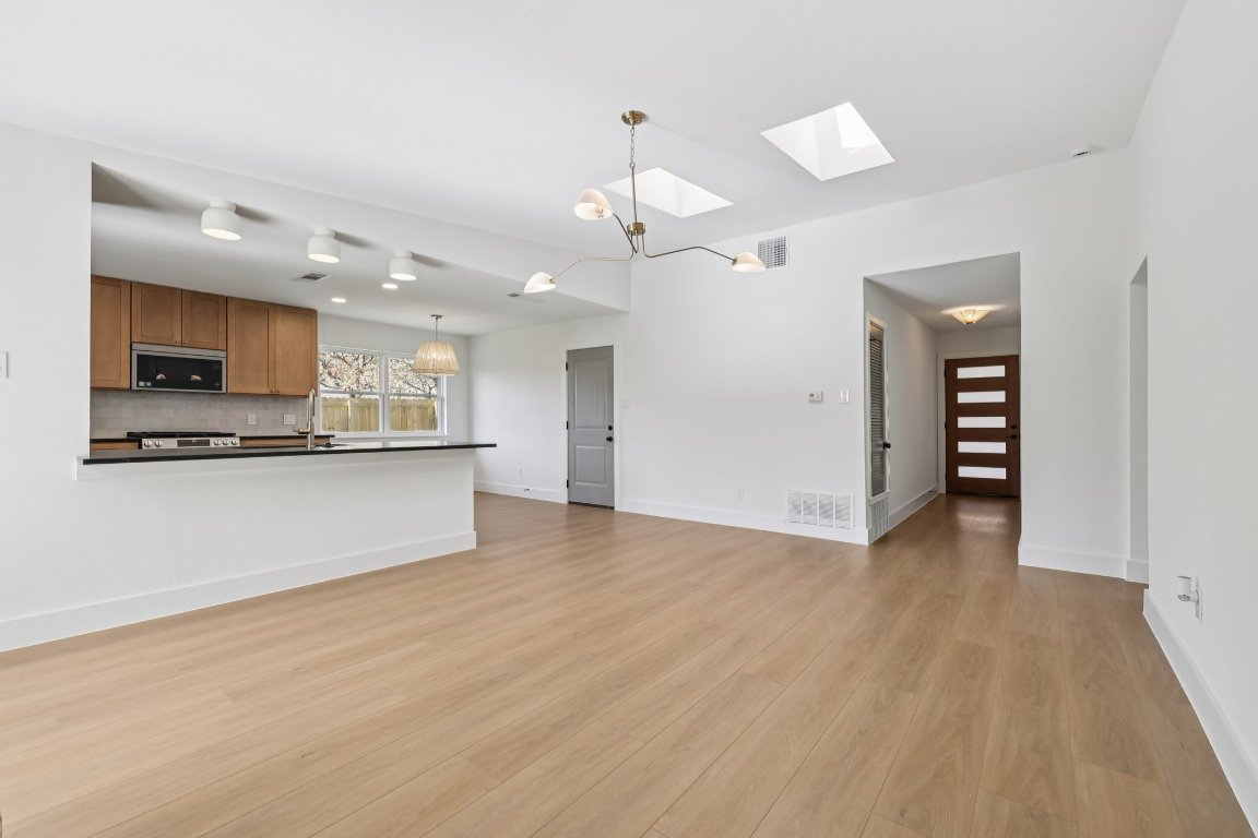 10424 Quail Ridge Drive Austin, TX 78758 - Photo 11 of 37 Unfurnished living room featuring a skylight, light wood-style floors, and a chandelier